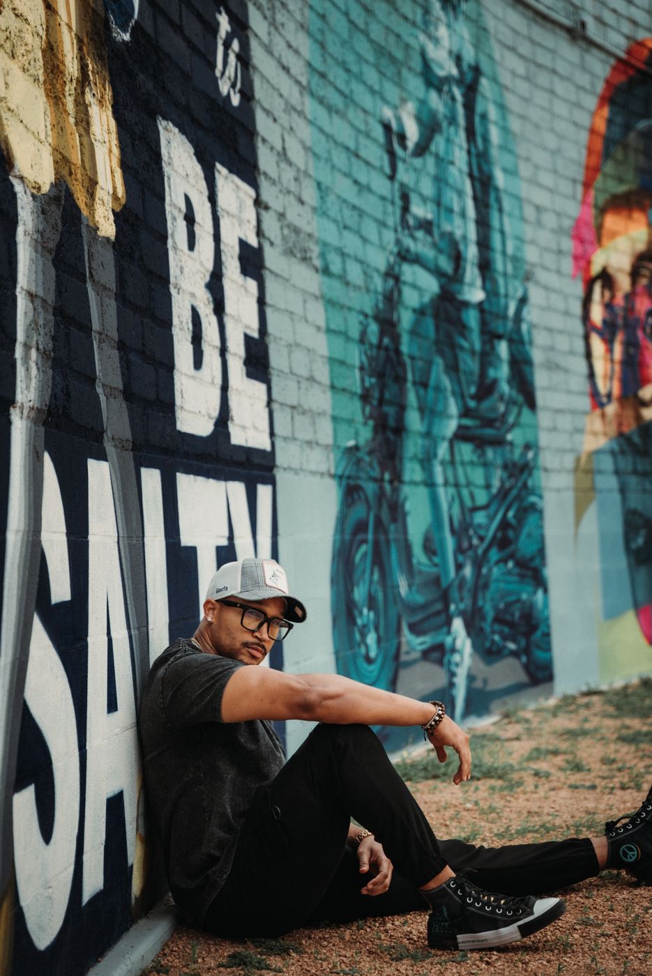 Real talk on dating — Marcus seated by the Be Salty mural